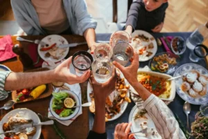 People toasting with drinks at a Thanksgiving feast.