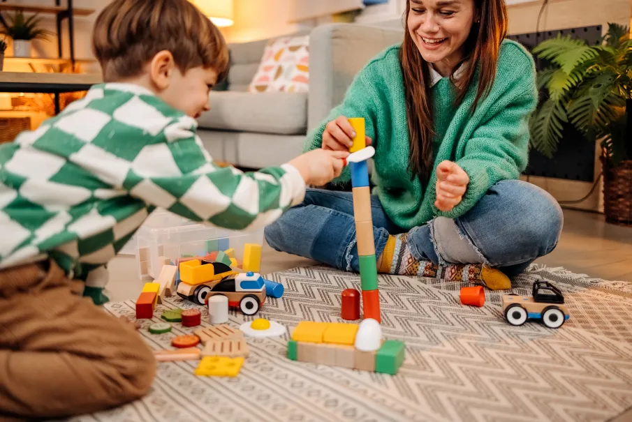 Mother and child playing with colorful building blocks on the floor