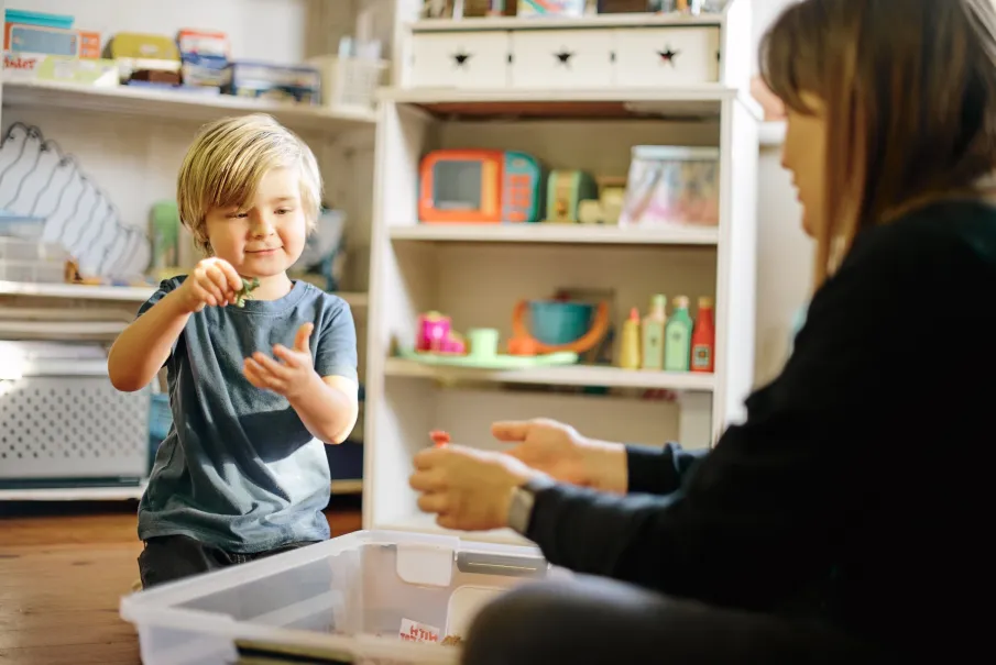 Child playing with toys in playroom with teacher