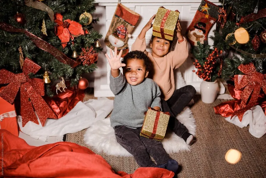 Children celebrating Christmas with gifts under decorated tree