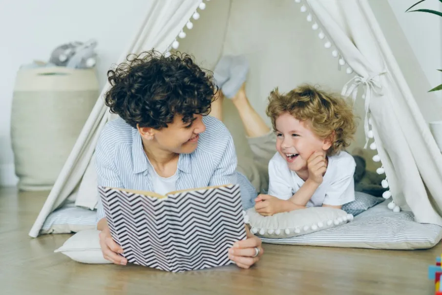 Parent reading a book to a child inside a cozy tent