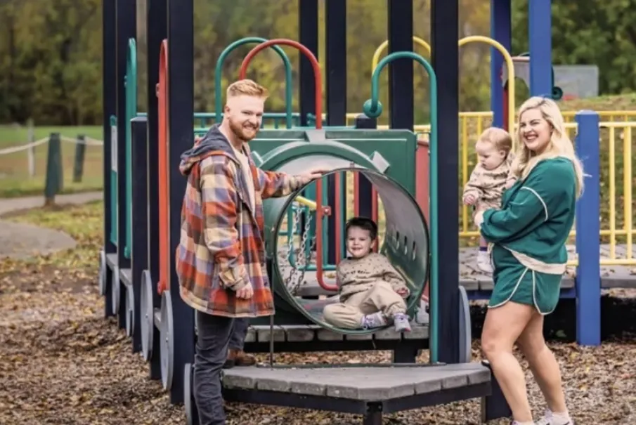 Family enjoying time at playground with two children in play area.