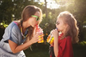 Mother and daughter enjoying drinks outdoors with sunglasses