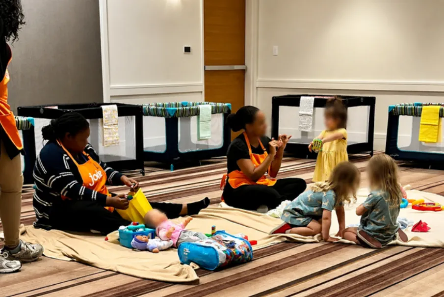 Children playing with caregivers in a daycare setting with toys and playpens