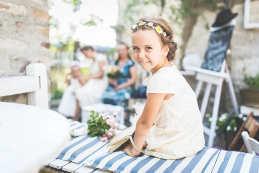 Young girl in a white dress smiling at a wedding