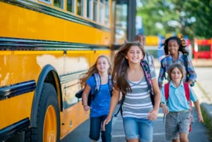 Kids happily getting off a yellow school bus with backpacks.