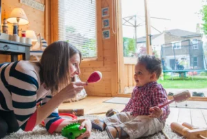 Mother playing with her baby using colorful toys in a sunlit room.