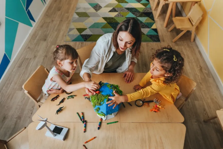Teacher and children engaged in an educational activity with a globe model and toys in classroom