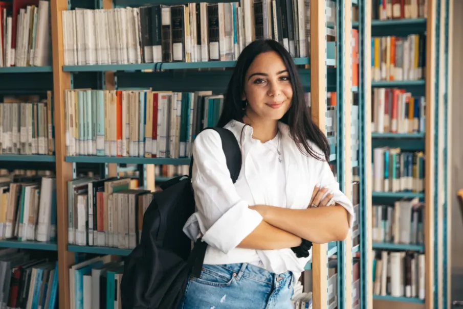 Student in a library with bookshelves