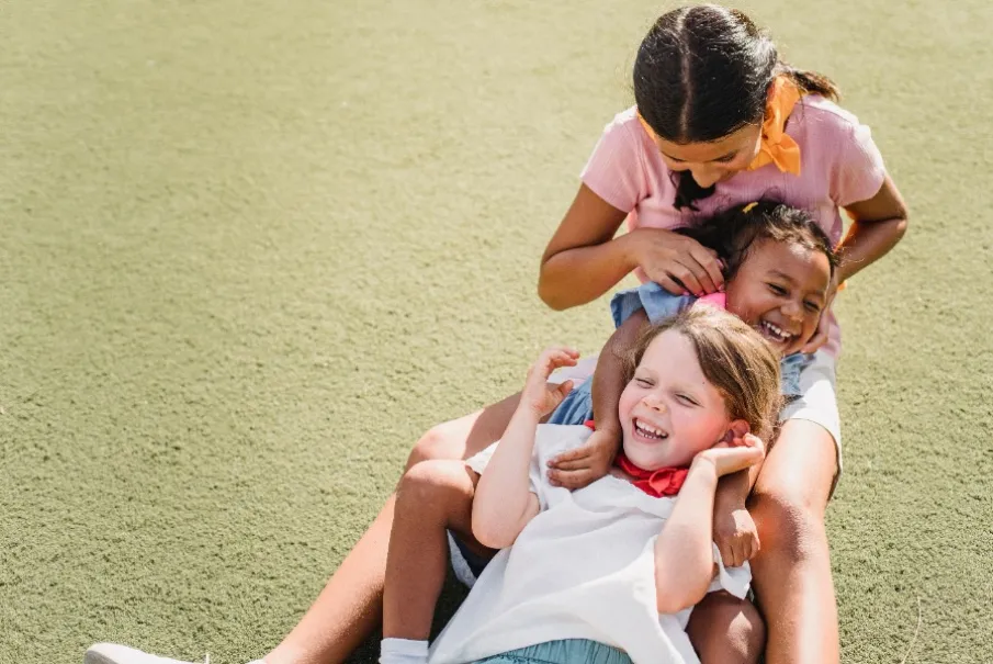 Children playing and laughing on grass in a park