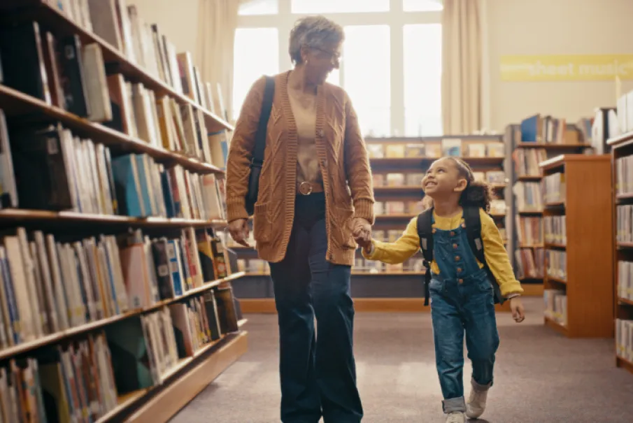 Grandmother and granddaughter walking hand in hand in a library