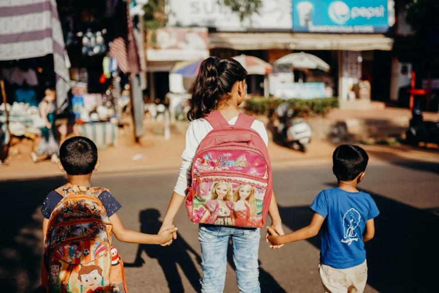 Children walking with colorful backpacks on a street