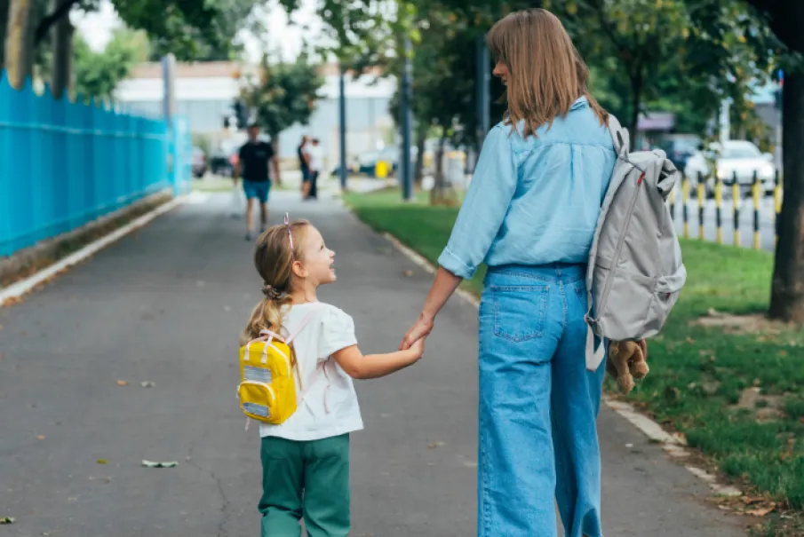 Mother holding daughter's hand on a city sidewalk