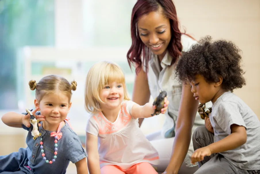 Children playing with toys and teacher in classroom setting