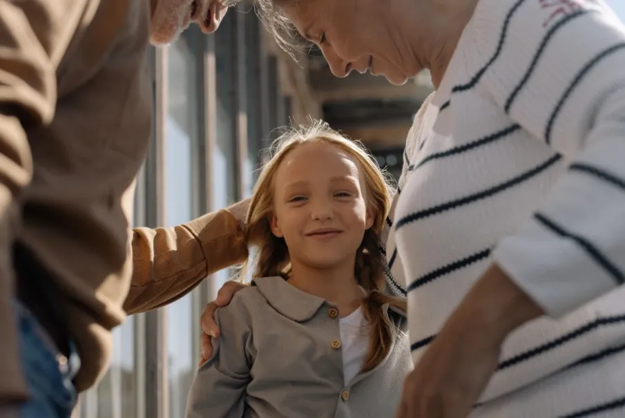 Elderly couple smiling at a young girl in a warm family moment