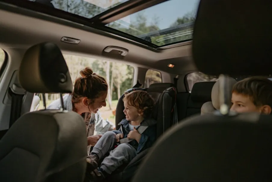 Mother smiling at child in car seat inside vehicle