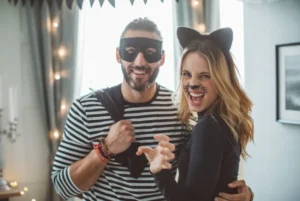 Couple in Halloween costumes with a man in a mask and a woman in a cat outfit.