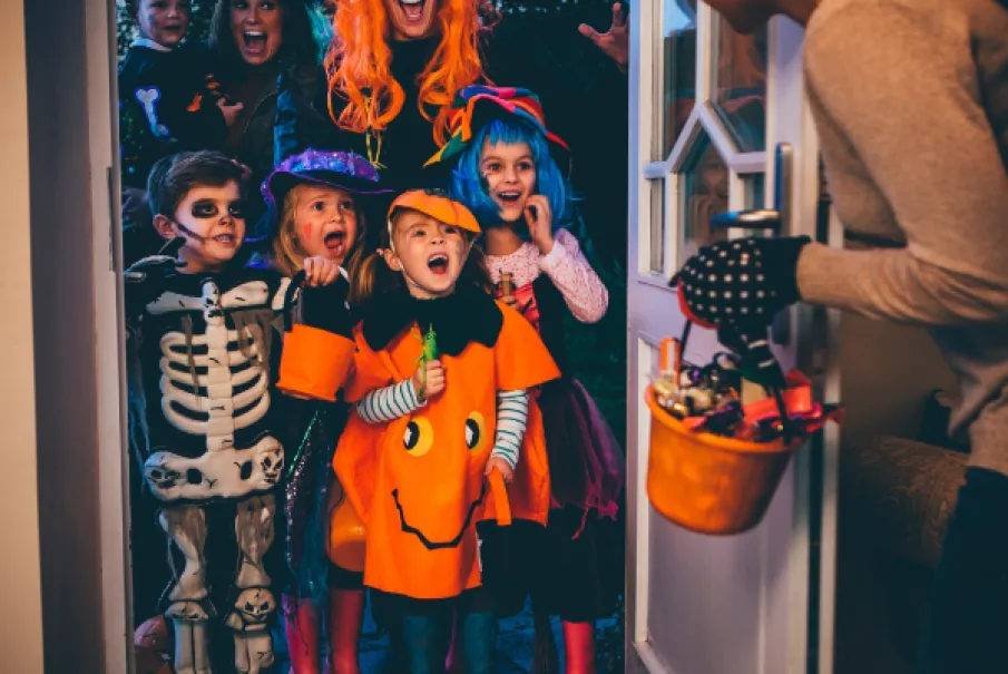 Children in Halloween costumes trick-or-treating at a door