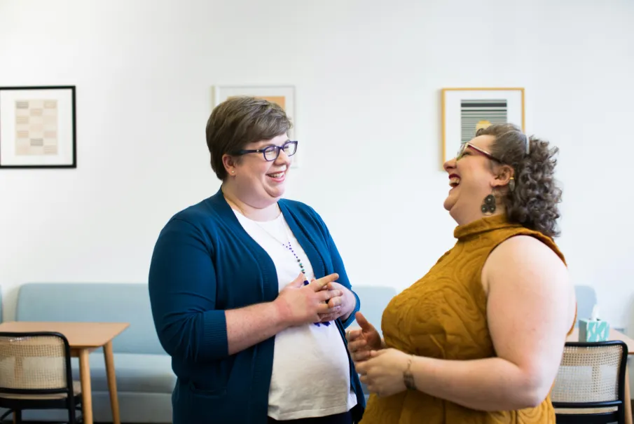 Two women laughing together in a bright room